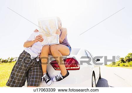 Couple at back of car looking at map View Large Photo Image Stock Photo - Couple at back of car looking at map. Fotosearch