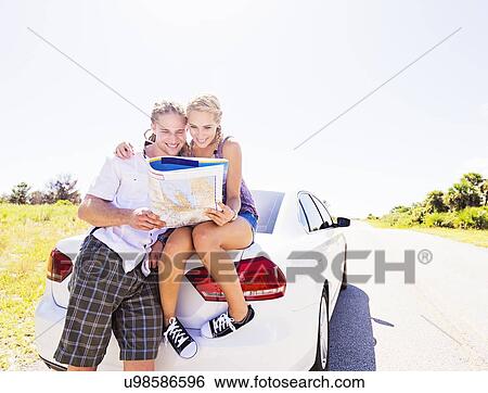 Couple at back of car looking at map View Large Photo Image Stock Photograph - Couple at back of car looking at map. Fotosearch