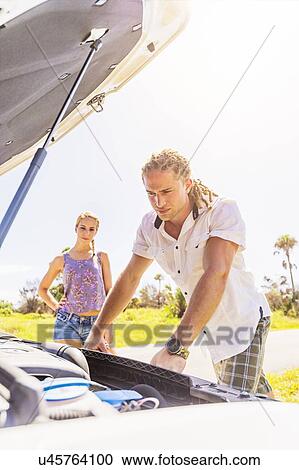 Stock Image - Couple checking car engine. Fotosearch