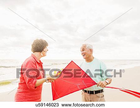 Couple flying kite together on beach View Large Photo Image Stock Image - Couple flying kite together on beach. Fotosearch