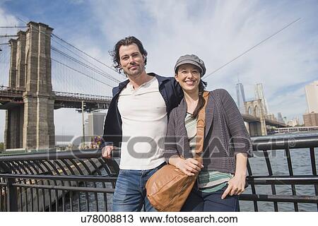 Couple leaning against railing and looking at camera View Large Photo Image Stock Image - Couple leaning against railing and looking at camera. Fotosearch