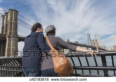 Stock Photo - Couple leaning against railing and looking at Freedom Tower . Fotosearch