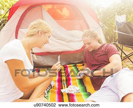 Stock Image - Couple playing cards in front of tent. Fotosearch