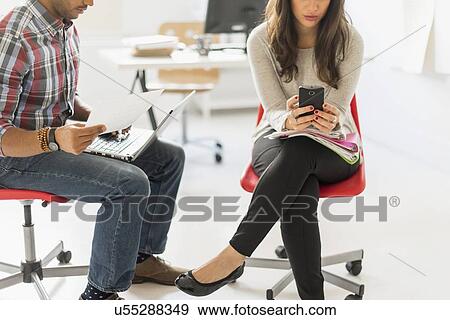 Couple sitting and working in office View Large Photo Image Stock Photo - Couple sitting and working in office. Fotosearch