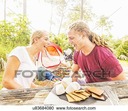Couple sitting at table with snacks View Large Photo Image Stock Image - Couple sitting at table with snacks. Fotosearch
