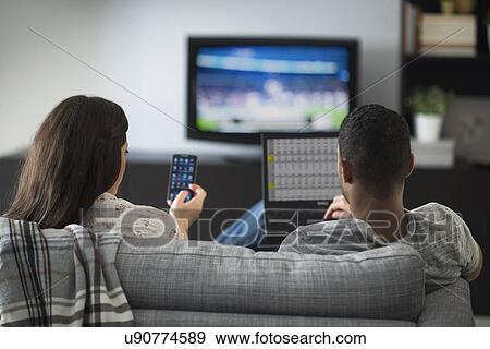 Couple sitting in living room, using laptop and cell phone View Large Photo Image Stock Photo - Couple sitting in living room, using laptop and cell phone. Fotosearch