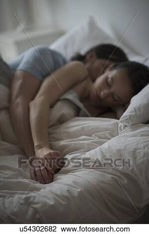 Stock Image - Couple sleeping together in bed at night. Fotosearch