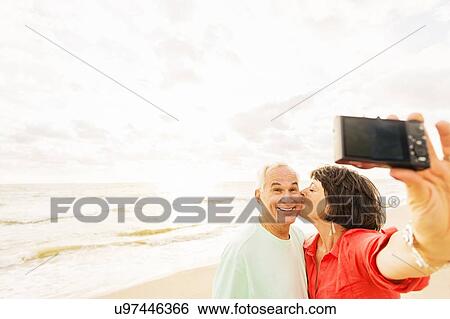 Couple taking selfie on beach at sunrise View Large Photo Image Stock Photograph - Couple taking selfie on beach at sunrise. Fotosearch