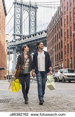Couple walking on street, Brooklyn Bridge in background View Large Photo Image Stock Image - Couple walking on street, Brooklyn Bridge in background. Fotosearch