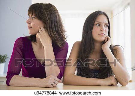 Picture - Frustrated teenage girl (14-15) and her mom sitting at table. Fotosearch