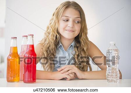 Girl (12-13) choosing between water and soda View Large Photo Image Stock Photograph - Girl (12-13) choosing between water and soda. Fotosearch