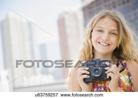 Girl (12-13) holding camera, smiling View Large Photo Image Stock Photo - Girl (12-13) holding camera, smiling. Fotosearch