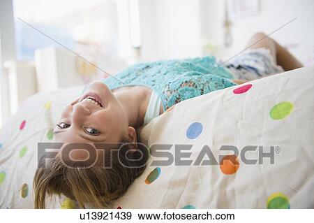 Girl (12-13) lying down on bed smiling View Large Photo Image Stock Photo - Girl (12-13) lying down on bed smiling. Fotosearch