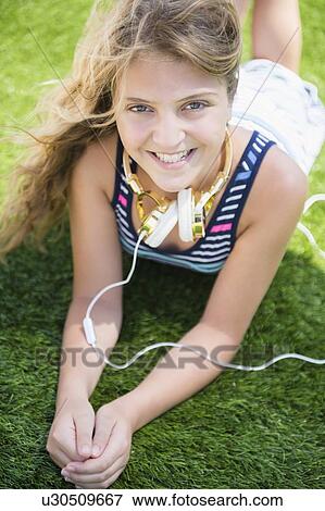 Girl (12-13) lying in grass with headphones View Large Photo Image Stock Photo - Girl (12-13) lying in grass with headphones. Fotosearch