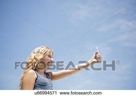 Stock Image - Girl (12-13) taking selfie. Fotosearch