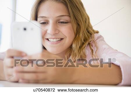 Stock Image - Girl (12-13) using smartphone. Fotosearch