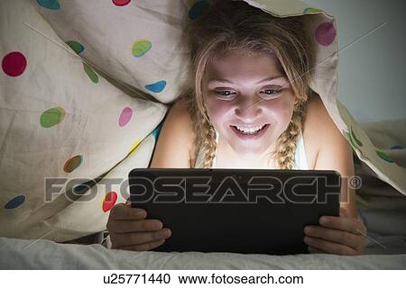 Girl (12-13) using tablet in bed View Large Photo Image Stock Image - Girl (12-13) using tablet in bed. Fotosearch