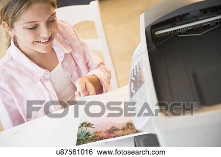 Stock Photograph - Girl (12-13) waiting for photo next to printer. Fotosearch