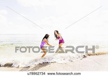 Girl (6-7) and her mom enjoying themselves on beach View Large Photo Image Picture - Girl (6-7) and her mom enjoying themselves on beach. Fotosearch
