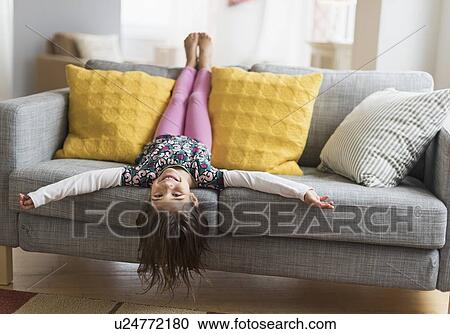 Girl (6-7) lying upside down on sofa View Large Photo Image Stock Image - Girl (6-7) lying upside down on sofa. Fotosearch