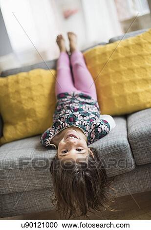 Girl (6-7) lying upside down on sofa View Large Photo Image Stock Image - Girl (6-7) lying upside down on sofa. Fotosearch