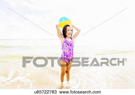 Girl (6-7) playing with ball on beach View Large Photo Image Stock Image - Girl (6-7) playing with ball on beach. Fotosearch