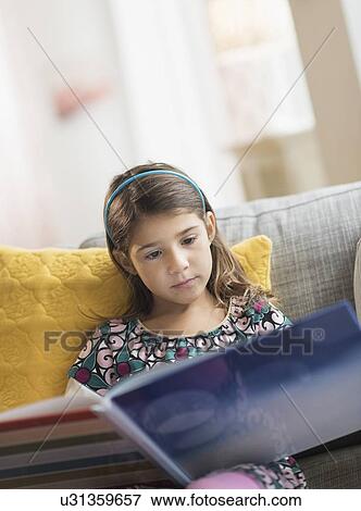 Stock Photo - Girl (6-7) reading book at home. Fotosearch