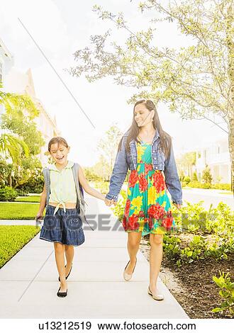 Girl (6-7) walking to school with her mom View Large Photo Image Stock Photo - Girl (6-7) walking to school with her mom . Fotosearch