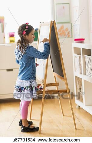 Girl (6-7) writing on board in classroom View Large Photo Image Picture - Girl (6-7) writing on board in classroom. Fotosearch
