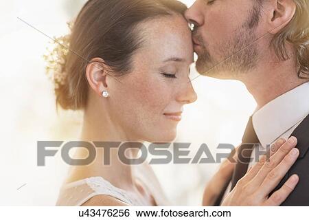 Stock Photograph - Groom kissing bride . Fotosearch
