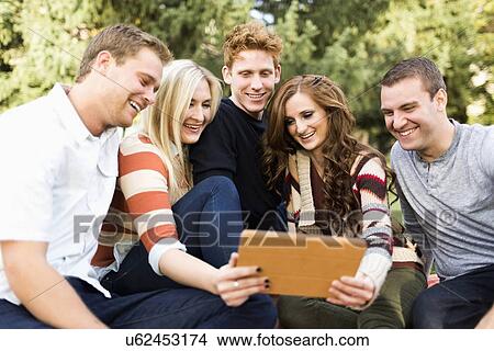 Group of friends looking at digital tablet View Large Photo Image Picture - Group of friends looking at digital tablet. Fotosearch