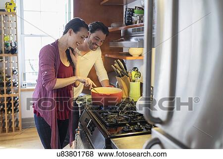 Stock Photo - Happy couple preparing dinner. Fotosearch