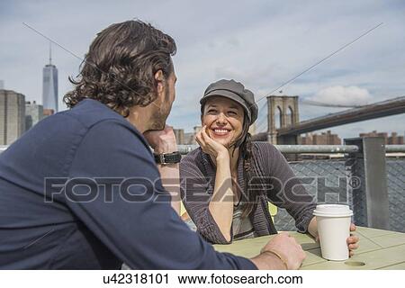 Happy couple sitting and discussing with cityscape in background View Large Photo Image Stock Image - Happy couple sitting and discussing with cityscape in background. Fotosearch