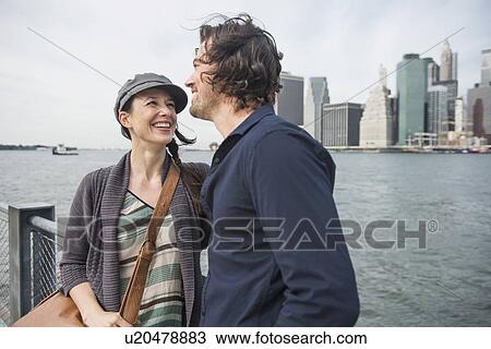 Stock Image - Happy couple standing against city skyline . Fotosearch