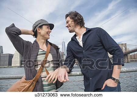 Stock Image - Happy couple standing and leaning against railing. Fotosearch