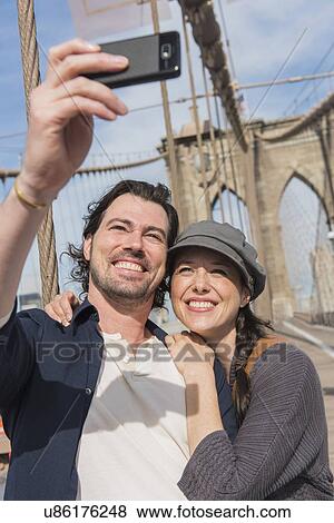 Happy couple taking selfie on Brooklyn Bridge View Large Photo Image Stock Photo - Happy couple taking selfie on Brooklyn Bridge . Fotosearch