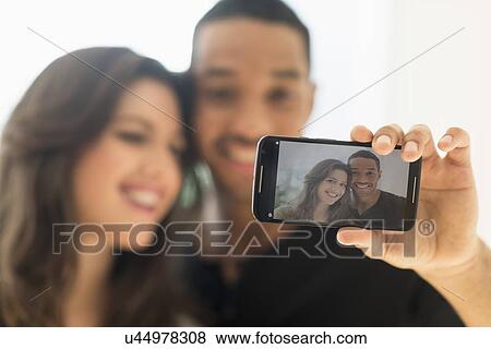 Stock Photo - Happy couple taking selfie . Fotosearch