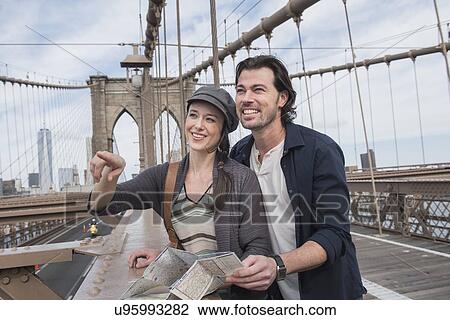 Stock Image - Happy couple with map on Brooklyn Bridge . Fotosearch