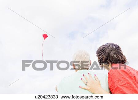 Low-angle view of couple flying kite together View Large Photo Image Stock Image - Low-angle view of couple flying kite together . Fotosearch