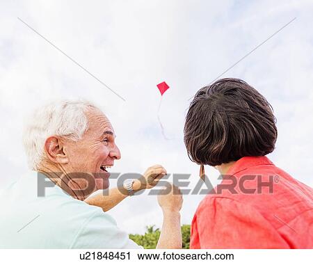 Low-angle view of couple flying kite together View Large Photo Image Stock Image - Low-angle view of couple flying kite together . Fotosearch