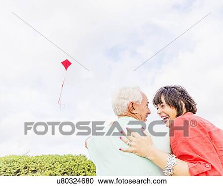 Low-angle view of couple flying kite together View Large Photo Image Stock Image - Low-angle view of couple flying kite together . Fotosearch