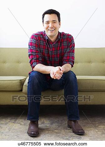 Man in checked shirt sitting on sofa and posing to camera View Large Photo Image Stock Photography - Man in checked shirt sitting on sofa and posing to camera. Fotosearch