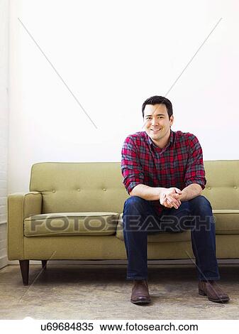Stock Photography - Man in checked shirt sitting on sofa. Fotosearch