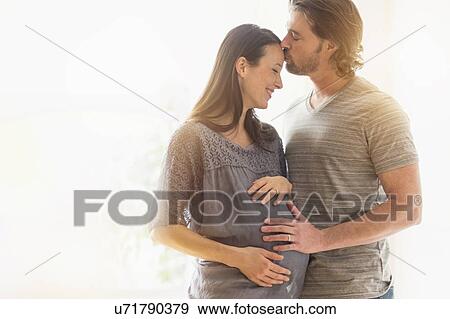 Stock Photo - Man kissing pregnant woman. Fotosearch