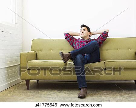 Man sitting on sofa with crossed legs and head in hands View Large Photo Image Stock Photograph - Man sitting on sofa with crossed legs and head in hands. Fotosearch