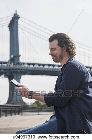 Stock Photo - Man using tablet pc, Manhattan Bridge in background. Fotosearch