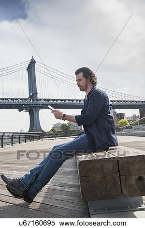 Man using tablet pc, Manhattan Bridge in background View Large Photo Image Stock Photography - Man using tablet pc, Manhattan Bridge in background. Fotosearch
