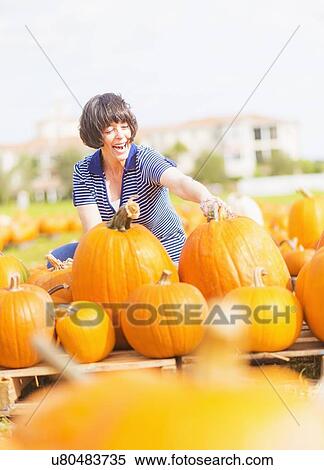 Mature woman picking up pumpkins View Large Photo Image Stock Photography - Mature woman picking up pumpkins . Fotosearch