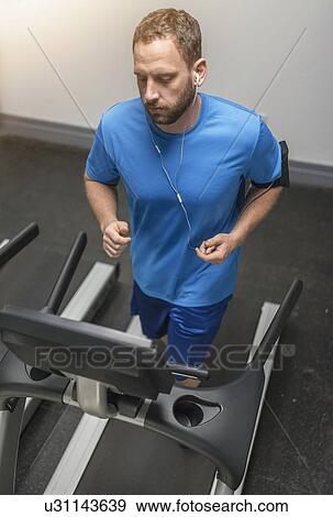 Stock Photo - Mid adult man exercising on treadmill. Fotosearch