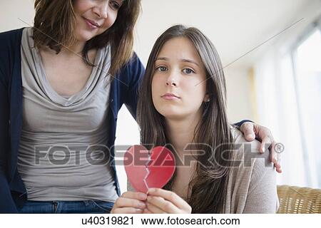Stock Image - Mom comforting her heartbroken teenage daughter (14-15). Fotosearch